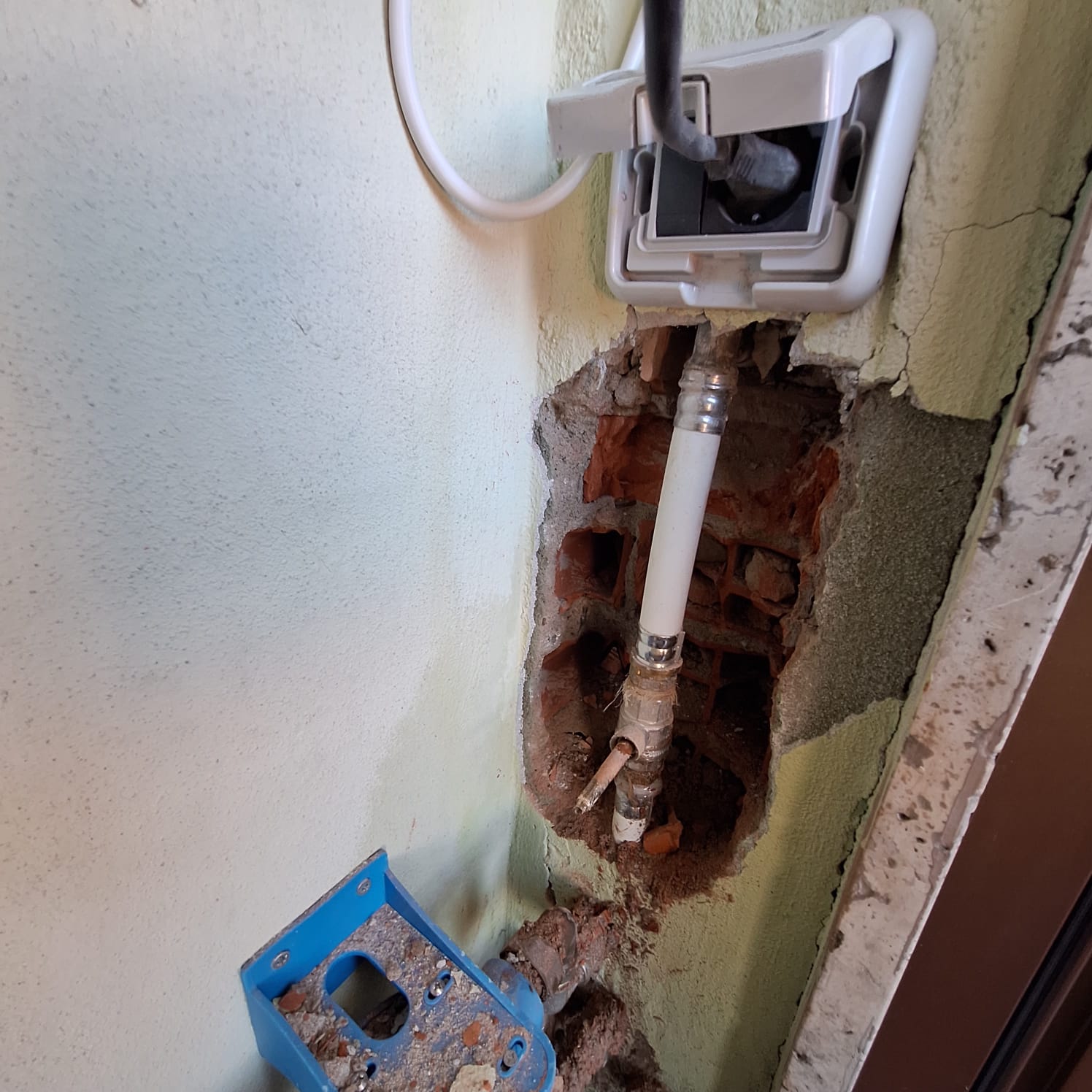 An exposed wall cavity contains vertical plumbing, fittings, and flexible tubing.